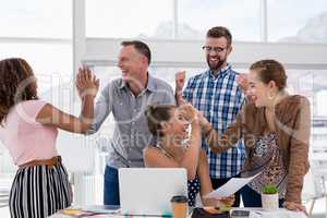 Team of executives giving high five to each other