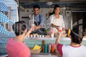 Waitress and waiter giving juice to customer at counter