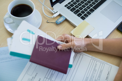 Female executive holding tickets and passport at her desk