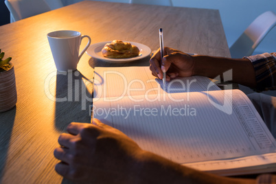 Male executive writing in diary at his desk