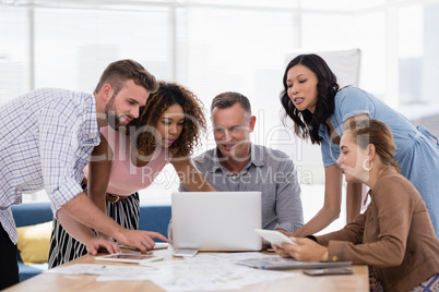 Team of executives discussing over laptop in the office