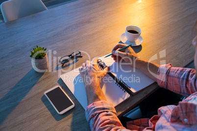 Male executive writing in diary at his desk