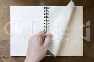 Hands turn pages of the notebook
