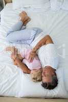 Father and daughter sleeping together on bed in bedroom