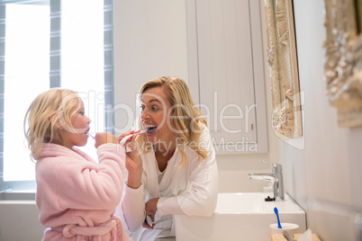 Mother and daughter brushing teeth in bathroom