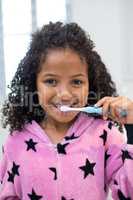 Smiling girl brushing her teeth in bathroom