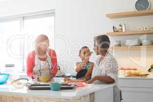 Girl feeding food to her grandmother in kitchen
