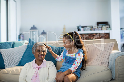 Granddaughter brushing her grandmothers hair in living room