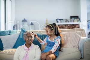 Granddaughter brushing her grandmothers hair in living room