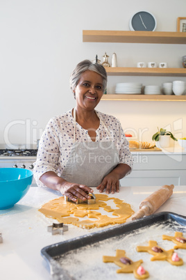 Smiling senior woman preparing cookies in kitchen