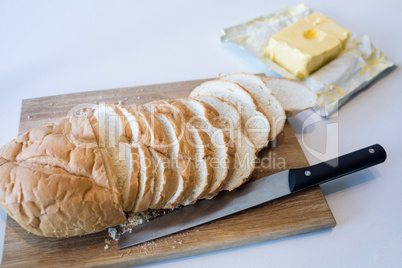 Slice of bread on chopping board with knife and butter in kitchen worktop