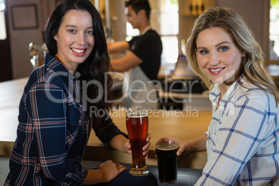 Portrait of female friends with bartender in background