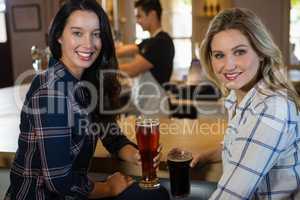 Portrait of female friends with bartender in background