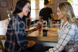 Female friends enjoying drinks with bartender in background