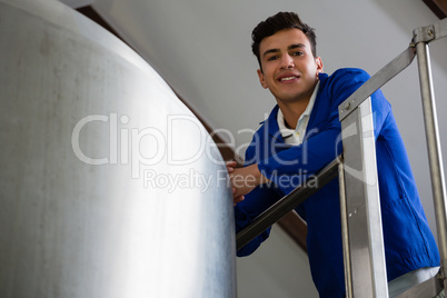 Low angle portrait of worker standing by storage tank