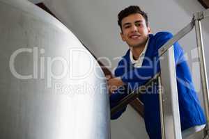 Low angle portrait of worker standing by storage tank