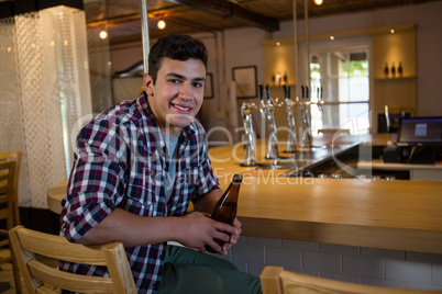 Portrait of man holding beer bottle at bar