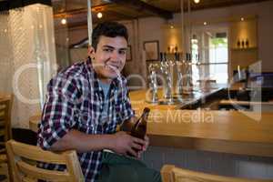 Portrait of man holding beer bottle at bar