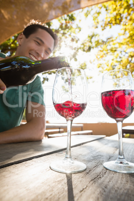 Man pouring red wine from bottle in glass