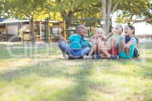 Cheerful children with arms around sitting at park