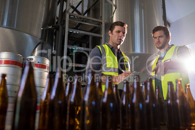 Coworkers discussing while pointing towards beer bottles
