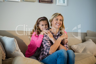 Mother and daughter embracing each other in the living room