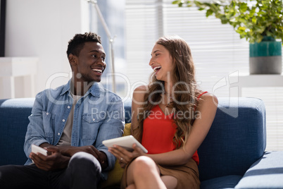 Male and female executives discussing over digital tablet in the office