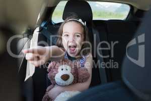 Excited girl holding teddy bear while gesturing in car