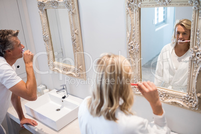 Couple brushing teeth in front of mirror