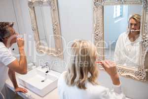 Couple brushing teeth in front of mirror