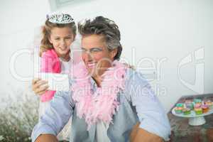 Cute daughter in fairy costume showing mobile phone to father