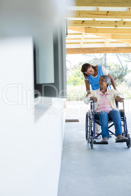 Female doctor pushing happy senior patient in wheelchair
