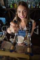 Portrait of beautiful barmaid pouring beer from tap in glass