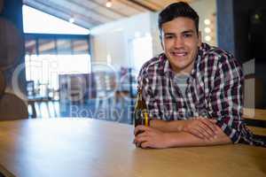 Portrait of smiling young man holding beer bottle