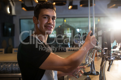 Portrait of bartender pouring beer from tap