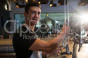 Portrait of bartender pouring beer from tap