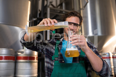 Portrait of smiling worker pouring beer in beaker