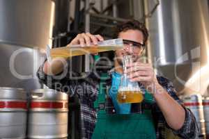 Portrait of smiling worker pouring beer in beaker