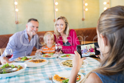 Girl photographing family through mobile phone