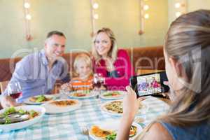 Girl photographing family through mobile phone