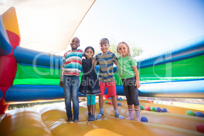 Portrait of friends with arms around standing on bouncy castle