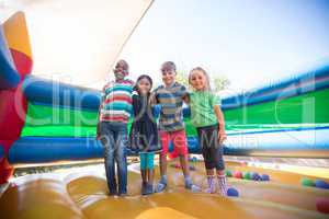 Portrait of friends with arms around standing on bouncy castle