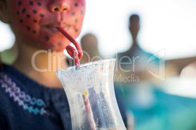 Girl with face paint having drink at park