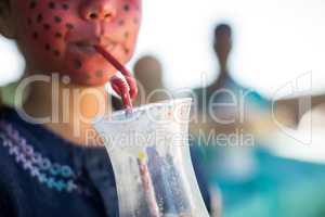 Girl with face paint having drink at park