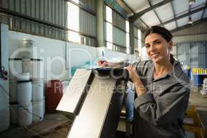 Female worker writing on clipboard in olive factory