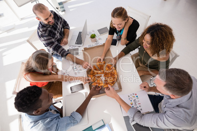 Happy executives sharing pizza in conference room