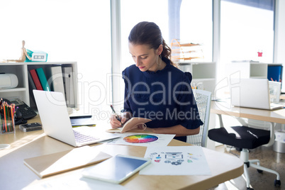 Female executive writing in diary at her desk