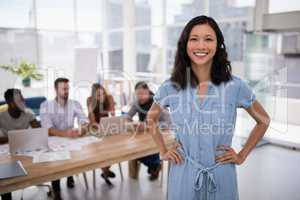 Female executive standing with hands on hip in the office
