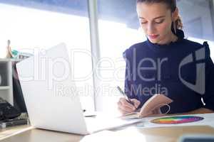 Female executive writing in diary at her desk