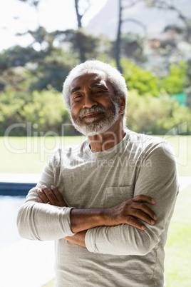 Senior man standing with arms crossed in the backyard